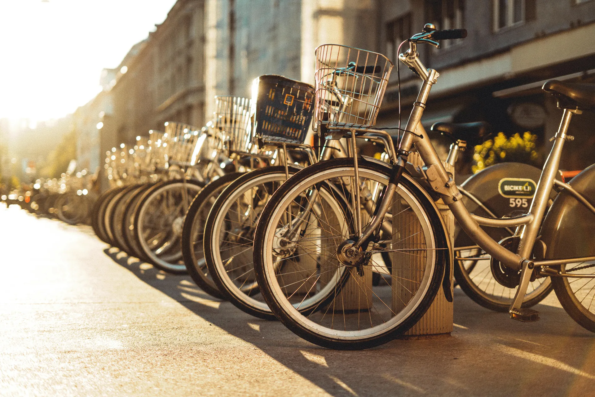 Sunlit row of parked bicycles on a Ljubljana street sidewalk, Slovenia.